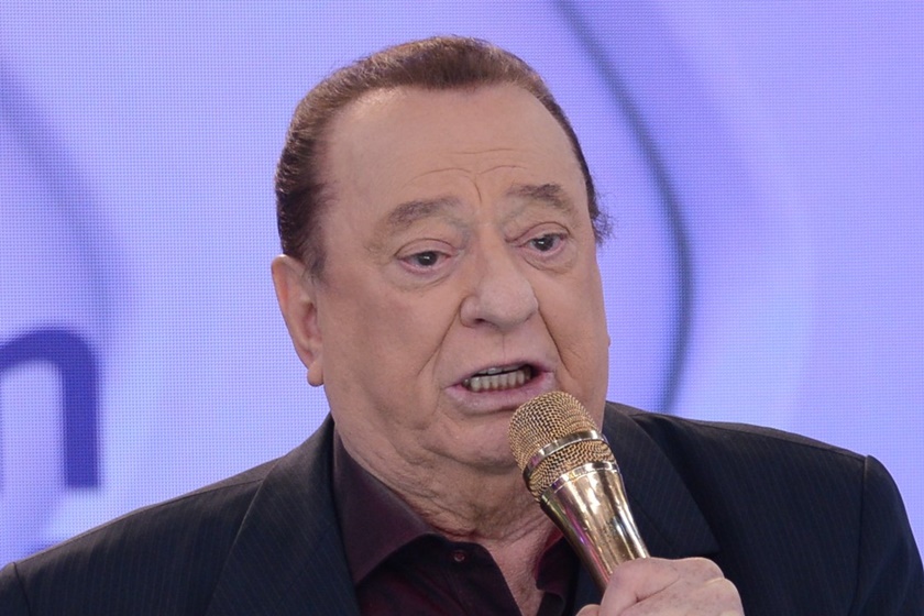 Foto colorida de Raul Gil com um microfone na mão - Metrópoles