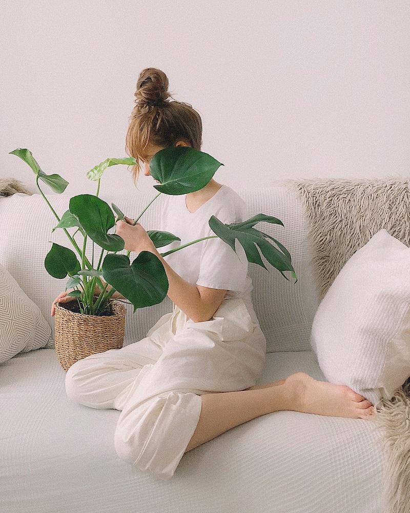 mulher jovem sentada em sofá ao lado de vaso de planta