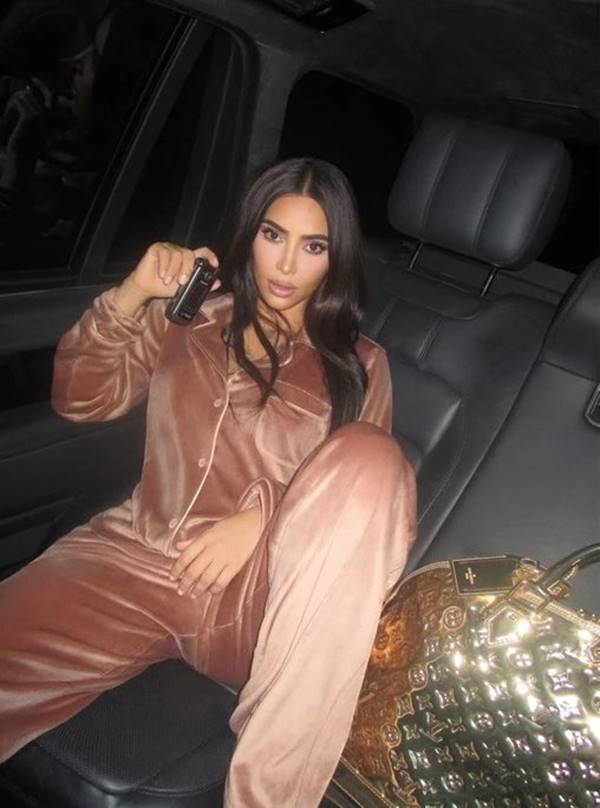 Kim Kardashian com conjunto de veludo, bolsa Louis Vuitton e celular flip