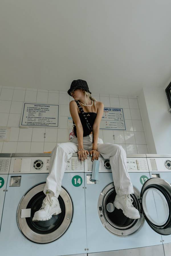 Garota sentada em cima de máquina de lavar