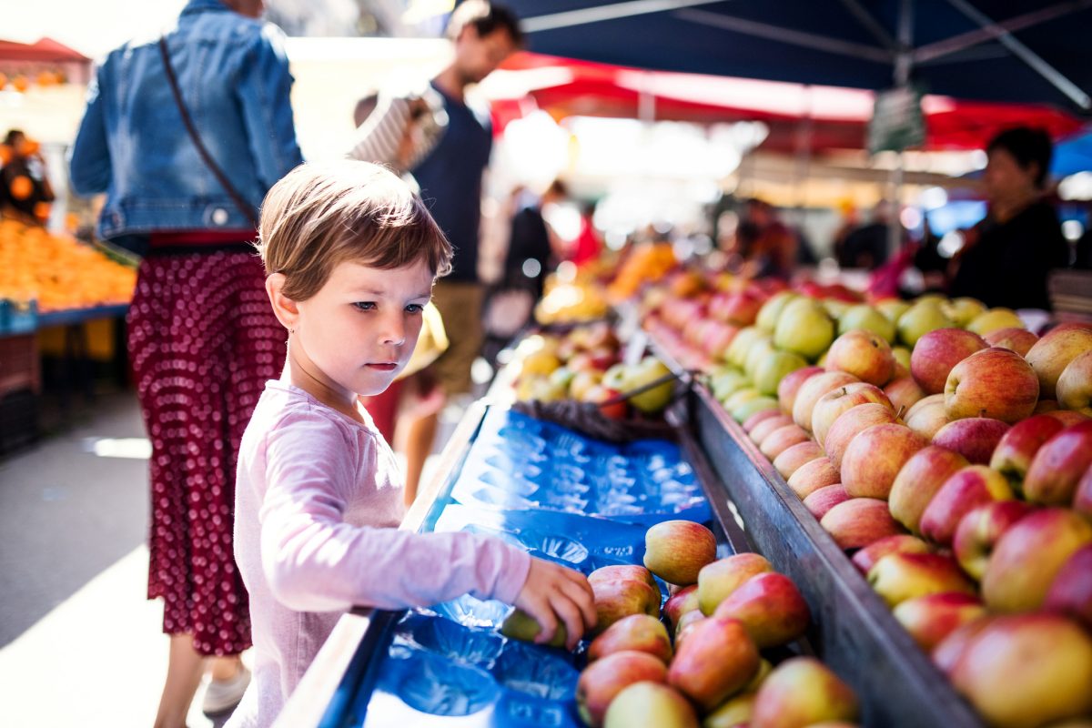 criança escolhendo frutas em supermercado