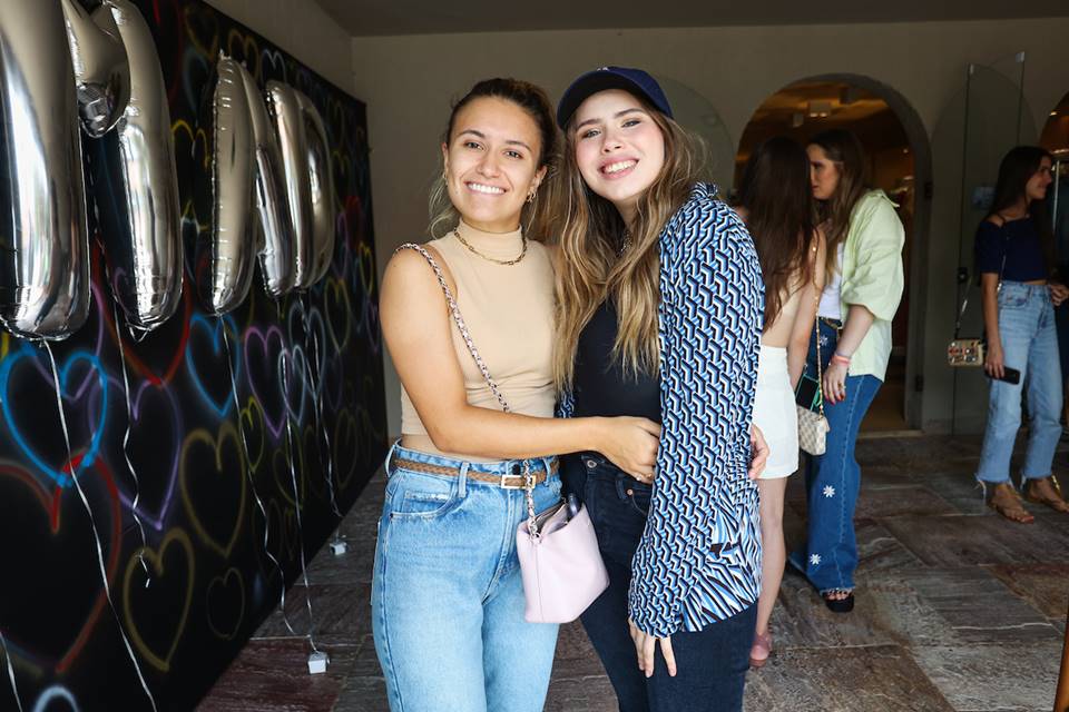 Duas adolescentes sorridentes posam para fotógrafo abraçadas 