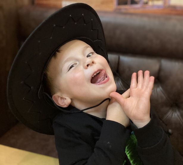Garoto Finlay, com um chapéu de cawboy, mostrando a língua e fazendo uma brincadeira com as mãos. O garoto é loiro, tem pele branca e os olhinhos de cor escura 