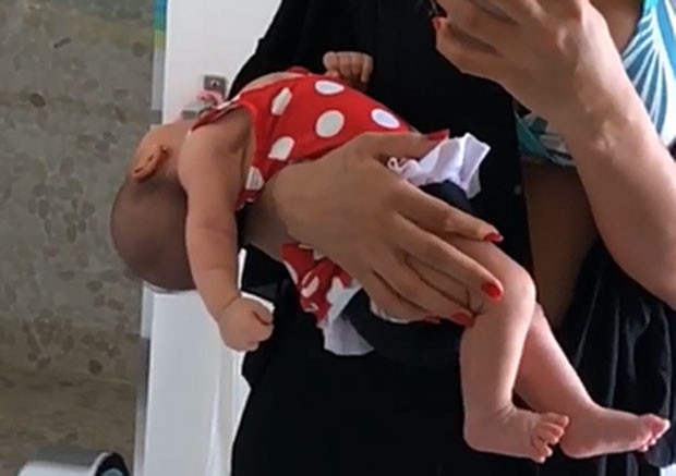 Fotografia colorida de Maíra segurando filha no colo