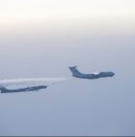 Em céu azul acinzentado com névoa, dois aviões fazem um rastro de fumaça no ar - Metrópoles