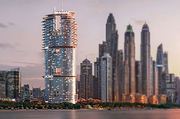 Prédio altíssimo em design futurista em Dubai. Ele está localizado em frente a um rio e, ao fundo, é possível ver prédios tão altos e luxuosos como ele