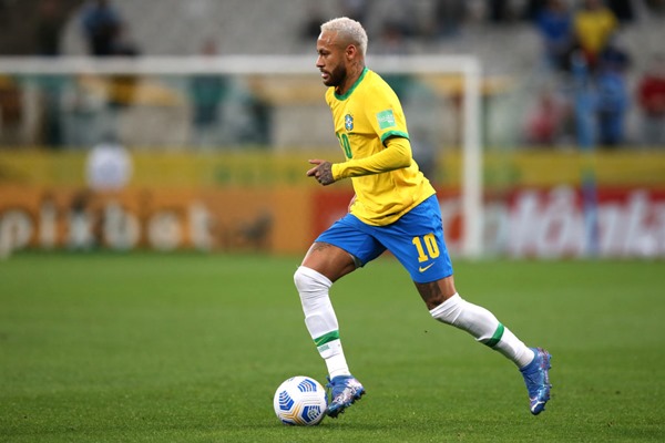 Neymar Júnior, jogador brasileiro de futebol. Ele tem cabelos descoloridos, usa uniforme de time de futebol e está correndo atrás de uma bola de futebol - Metrópoles