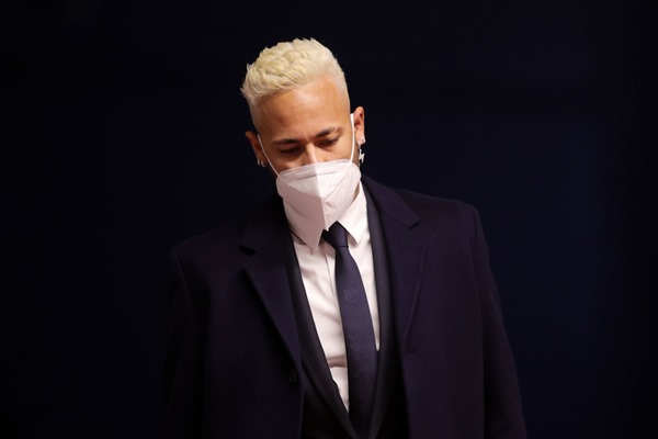 Neymar Júnior, jogador brasileiro de futebol. Ele tem cabelos descoloridos, usa terno e gravata e está com máscara branca no rosto– Metrópoles