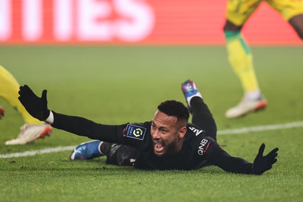 Neymar Júnior, jogador brasileiro de futebol. Ele tem cabelos escuros, usa uniforme de time de futebol e está caído no chão com as mãos para cima - Metrópoles
