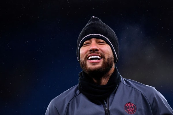 Neymar Júnior, jogador brasileiro de futebol. Ele tem cabelos escuros, usa uniforme de time de futebol e sorri enquanto olha para a frente - Metrópoles