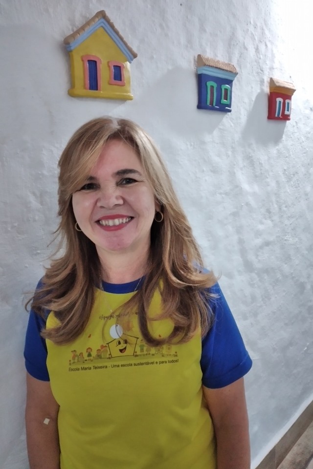 Foto colorida. Silvana Vasconcelos com uma blusa amarela e azul