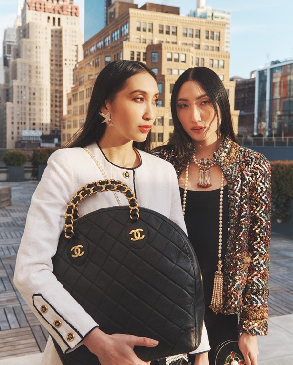 Duas mulheres asiáticas com cabelos lisos e pretos posam para foto em rua movimentada de Nova York. Elas usam peças da marca Chanel - Metrópoles