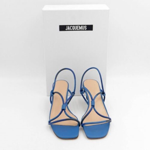 Sandália de salto azul com tiras entrelaçadas da marca Jacquemus. O salto do sapato possui pequenas esferas marrons, de diferentes madeiras