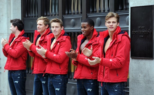 Na imagem com cor, quatro homens usam casaco vermelho enquanto batem palma