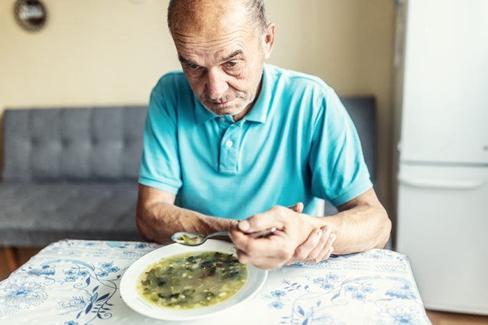 Idoso com camiseta azul sentado e comendo- Metrópoles