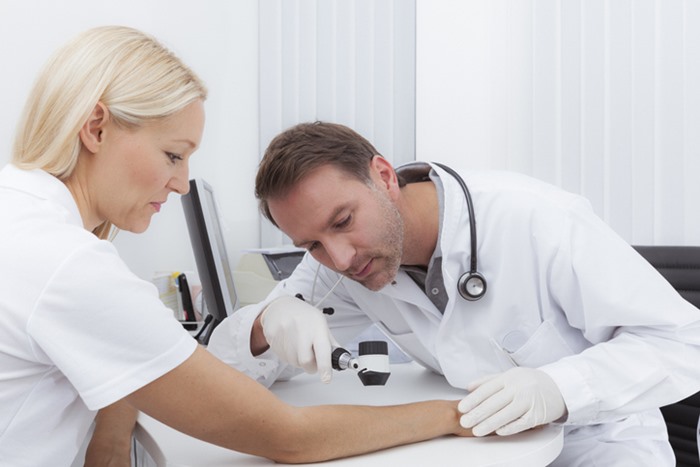 Médico investigando pele de paciente- Metrópoles