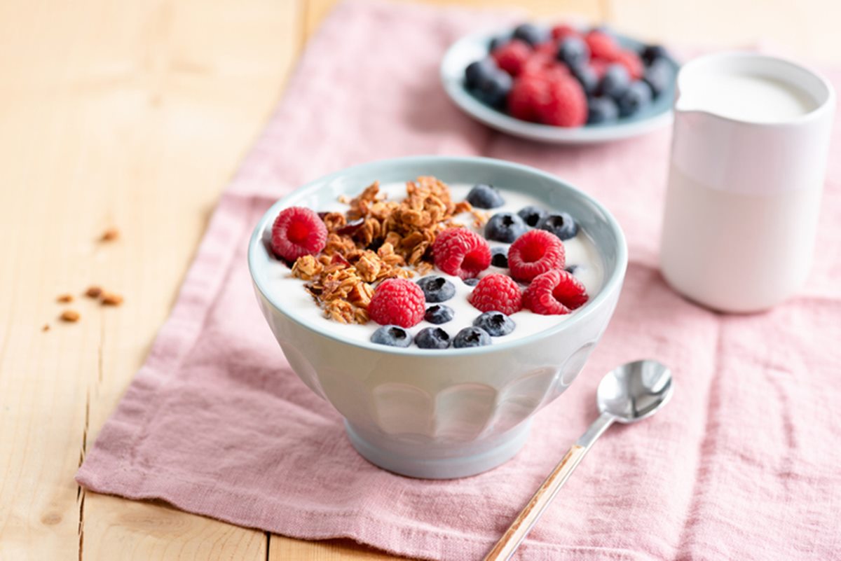 Na imagem, duas tigelas de iogurte branco com morango, mirtilo e granola em cima - Metrópoles