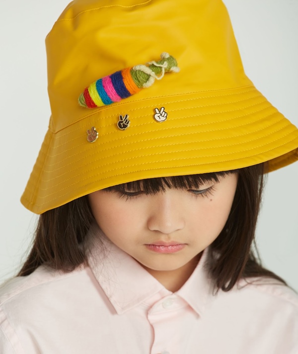 Campanha de divulgação da Simples, submarca da Reserva, onde modelos posam com as roupas em um fundo branco. Na foto, uma criança com traços asiáticos, cabelo liso e de franja preto, usa um chapéu amarelo.