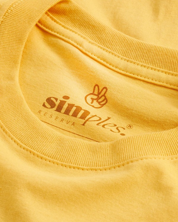 Gola de uma camiseta amarela com a etiqueta da marca. A peça é da Simples, nova marca do grupo Reserva.