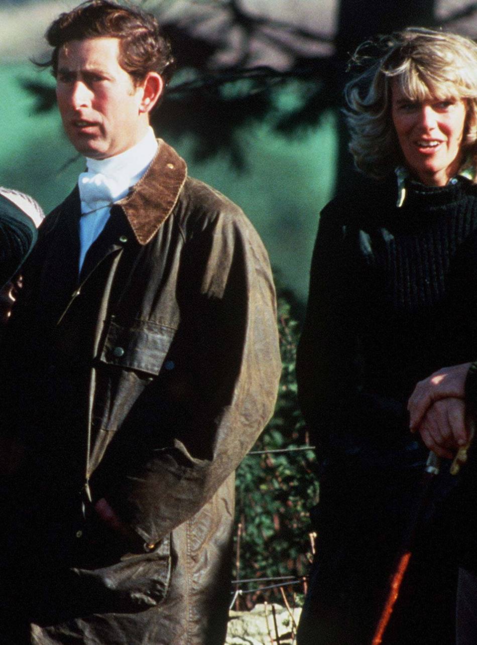 Príncipe Charles e Camilla Parker-Bowles em 1979 na floresta. Eles usam casacos pesados de inverno em nas cores preta e verde. - Metrópoles