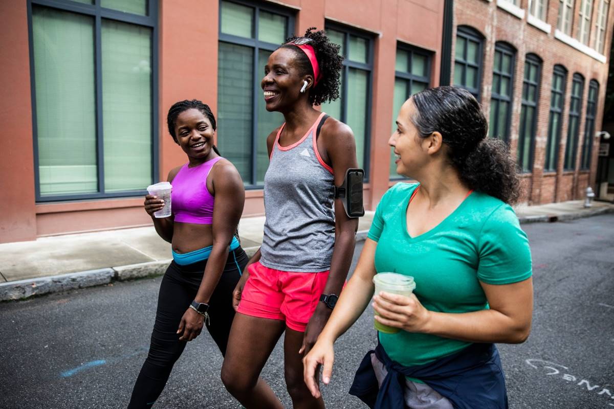 Foto colorida de três mulheres caminhando sorrindo
