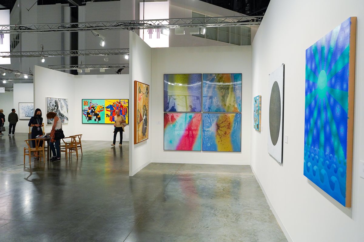 Galeria de arte no evento Art Basel, em Miami, em 2021. Na imagem é possível ver paredes brancas com obras de arte penduradas e pessoas admirando as peças de forma aleatória. - Metrópoles