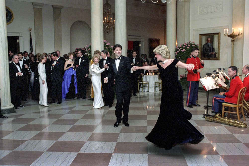 Nesta imagem fornecida pela Casa Branca, a princesa Diana dança com John Travolta no Cross Hall da Casa Branca durante um jantar oficial em 9 de novembro de 1985 em Washington, DC. Ele usa um smoking tradicional e ela usa um vestido longo preto, de veludo, com alças ombro a ombro. - Metrópoles