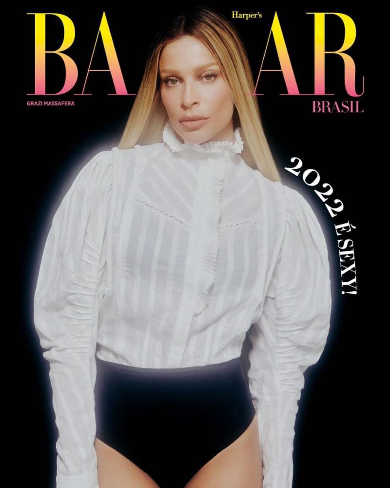 A ex-BBB e atriz Grazi Massafera, uma mulher jovem e branca, de cabelo liso loiro, posa para foto de capa da revista Harper's Bazaar Brasil. Ela usa uma blusa branca com mangas bufantes e detalhes de renda. - Metrópoles