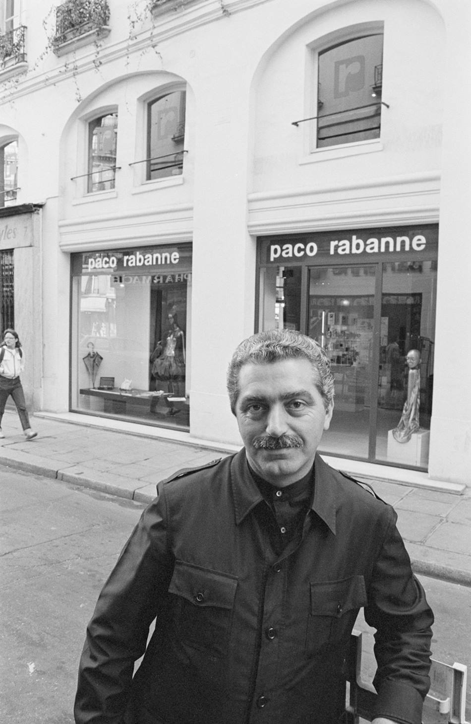 O estilista Paco Rabanne, um homem branco e de meia idade, com cabelos e barba grisalhos, posa para foto em uma loja de roupa da sua própria marca. - Metrópoles