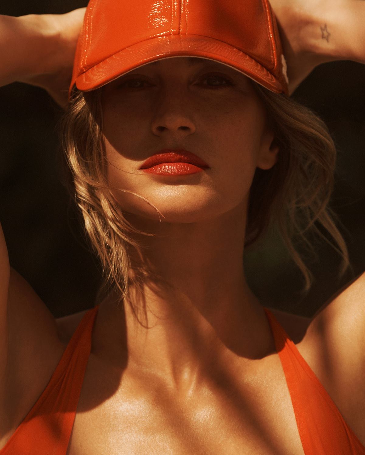 A modelo Gisele Bündchen, uma mulher branca e de meia idade, com cabelo loiro ondulado, posa para foto em praia na Costa Rica. Os cliques são da revista Vanity Fair. Gisele usa um maiô laranja e um chapéu, também laranja, invernizado. - Metrópoles