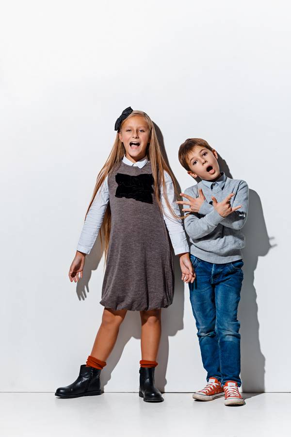 Duas crianças posando para foto em fundo branco - Metrópoles