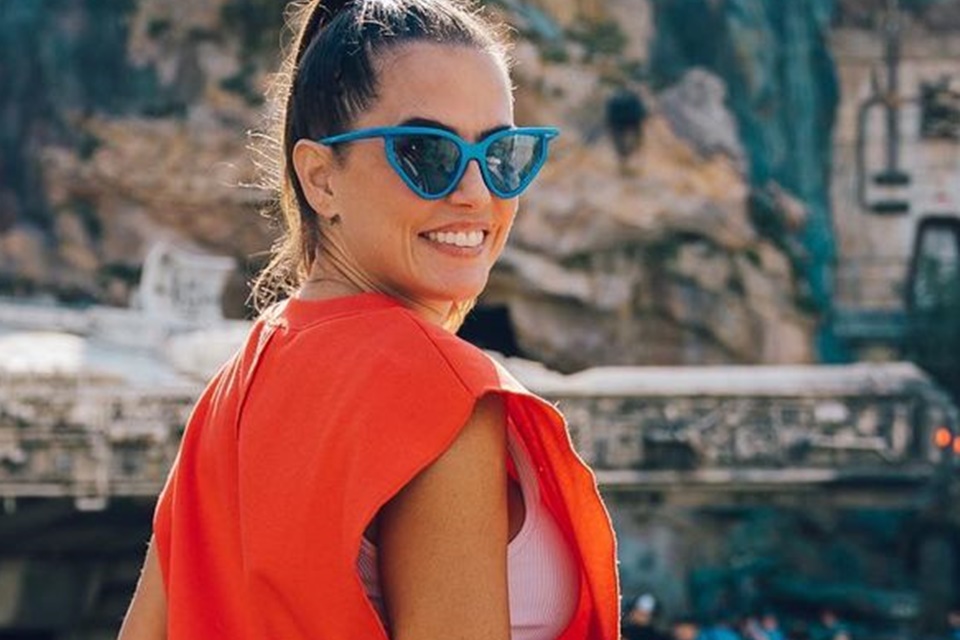 Foto colorida de Deborah Secco usando um óculos com base azul e uma regata laranja - Metrópoles