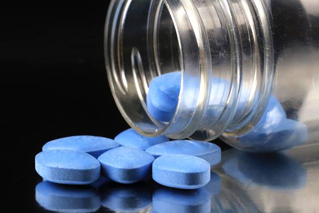 Imagem mostra vidro deitado e várias pílulas azuis de viagra - Metrópoles