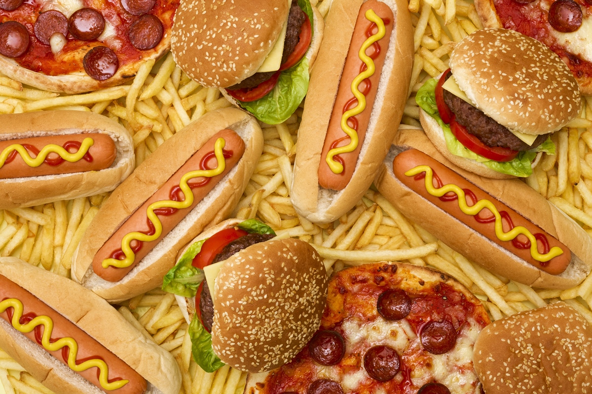 Foto colorida de hambúrgueres e cachorros-quentes rodeados de batatas-fritas - Metrópoles