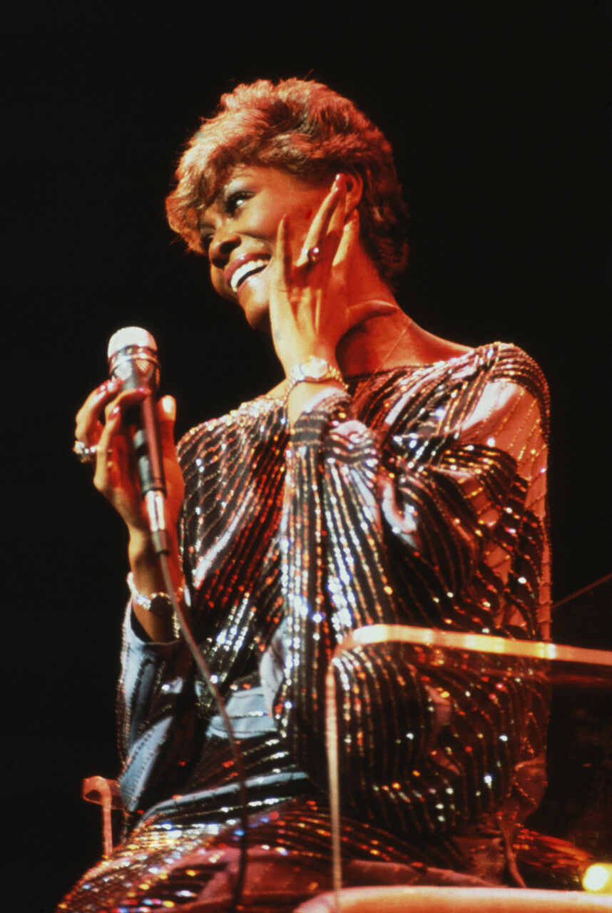 Na imagem com cor, uma mulher negra com um microfone na mão - Metrópoles