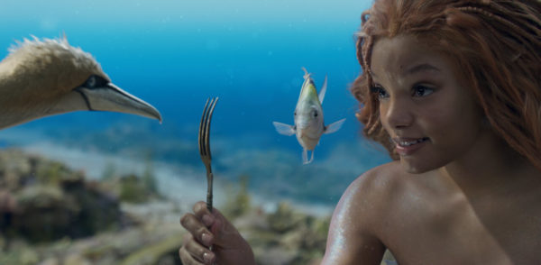 Na imagem com cor, uma mulher negra debaixo da água com um peixe - Metrópoles