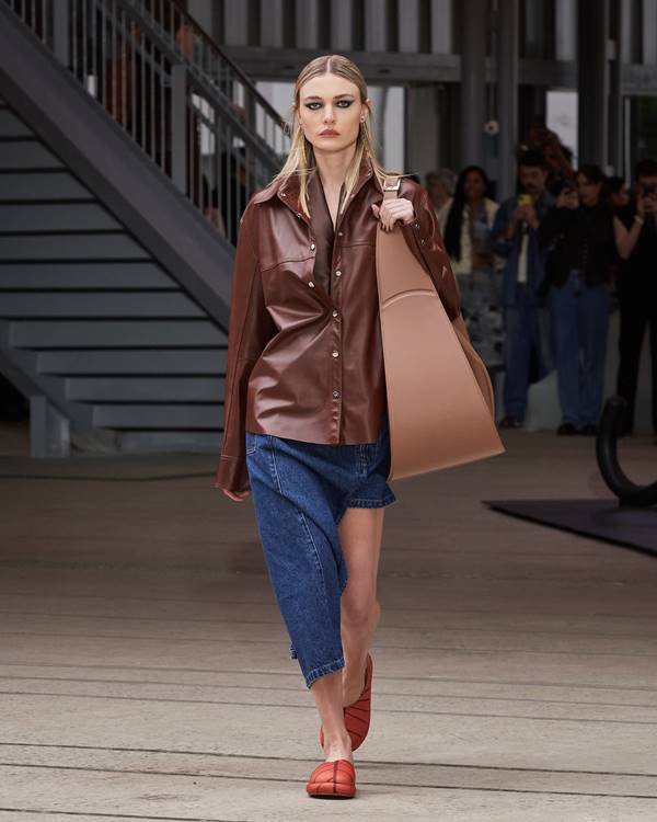 Na passarela da Misci, modelo usa saia jeans assimétrica com blusa marrom de couro e bolsa maxi - Metrópoles