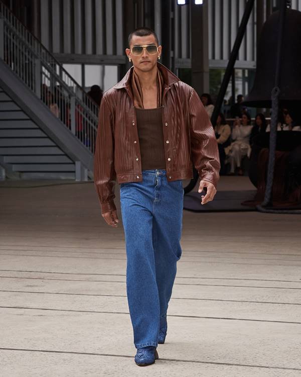 Na passarela da Misci, modelo usa calça jeans com jaqueta marrom de couro plissado - Metrópoles