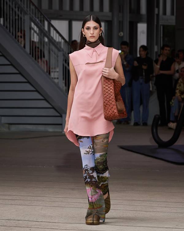 Na passarela da Misci, modelo usa bolsa marrom de couro de pirarucu em look com blusa rosa alongada e calça com estampa de natureza - Metrópoles