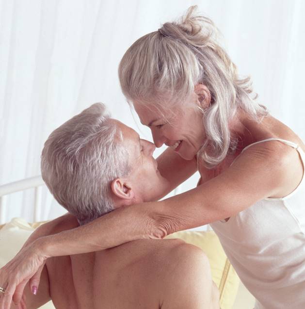 Foto colorida de casal de idosos deitado na cama - Metrópoles