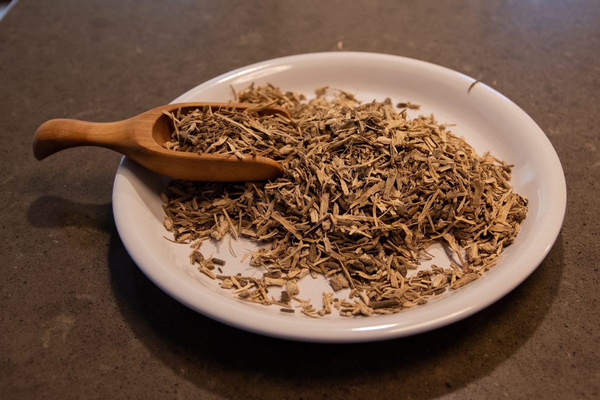 Foto de rizomas de kava kava em um prato bege e há uma colher de pau dentro - Metrópoles