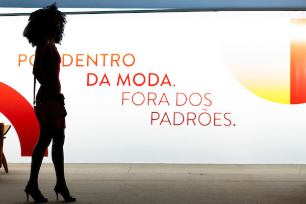 Na imagem com cor, a sombra de uma mulher negra na frente do fundo branco escrito "Moda Fora dos Padrões" - Metrópoles