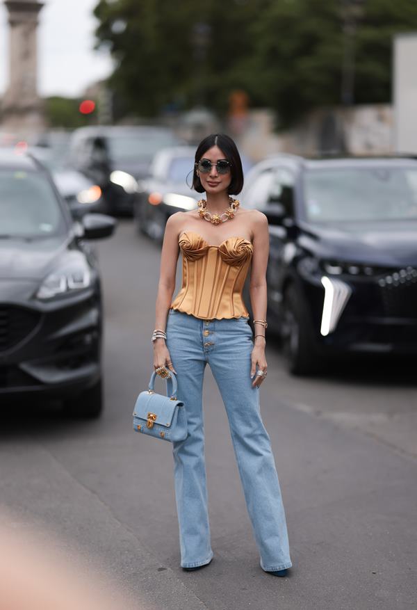 Mulher andando na rua com par de calças jeans - Metrópoles