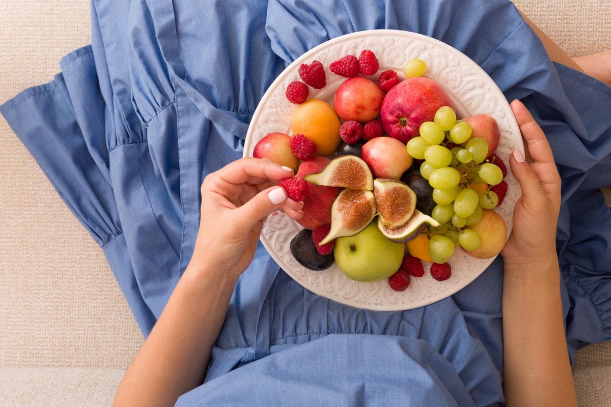 Foto de mão feminina segurando prato com uma variedade de frutas - Metrópoles