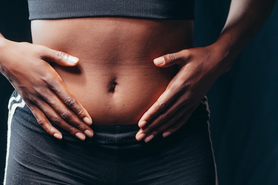 Na foto, uma mulher com roupas de academia e segurando a barriga - Metrópoles