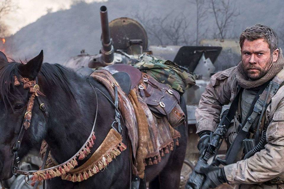 Imagem colorida de um cavalo preto e do ator Chris Hemsworth, protagonista do filme 12 Heróis - Metrópoles 