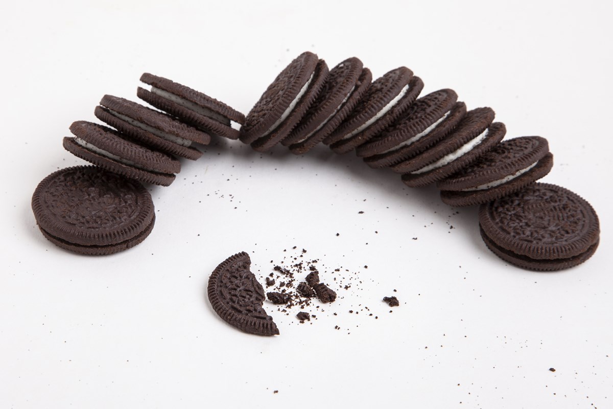 Foto colorida de 11 biscoitos recheados em fila. Uma camada de chocolate e a outra de baunilha. Uma parte está quebrada na frente - Metrópoles