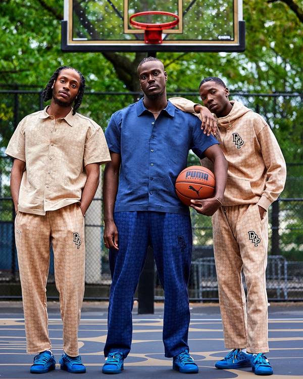 Três homens em quadra de basquete usando looks esportivos em bege e azul - Metrópoles