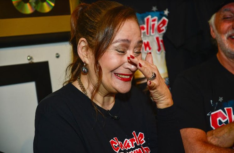 Foto colorida de Sonia Abrão chorando usando a blusa de Chorão - Metrópoles