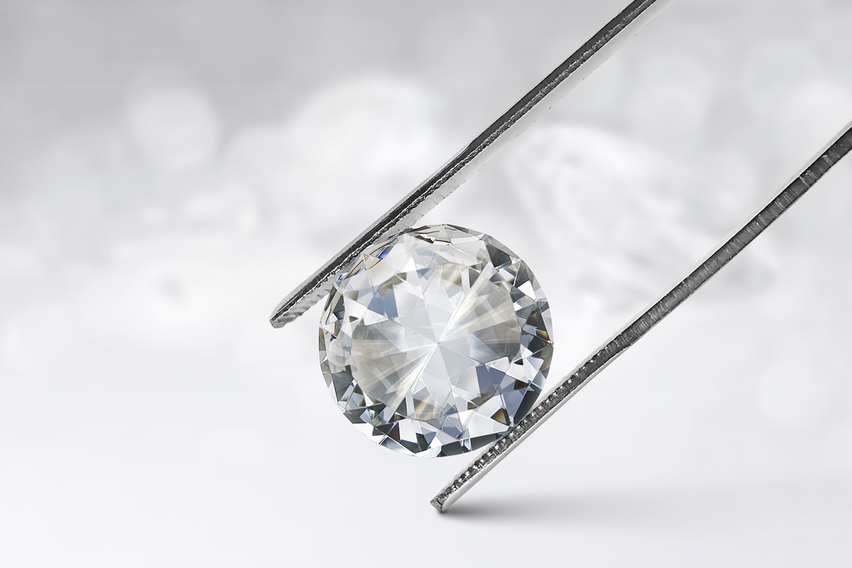 pinça segurando um diamante com fundo branco brilhante - Metrópoles